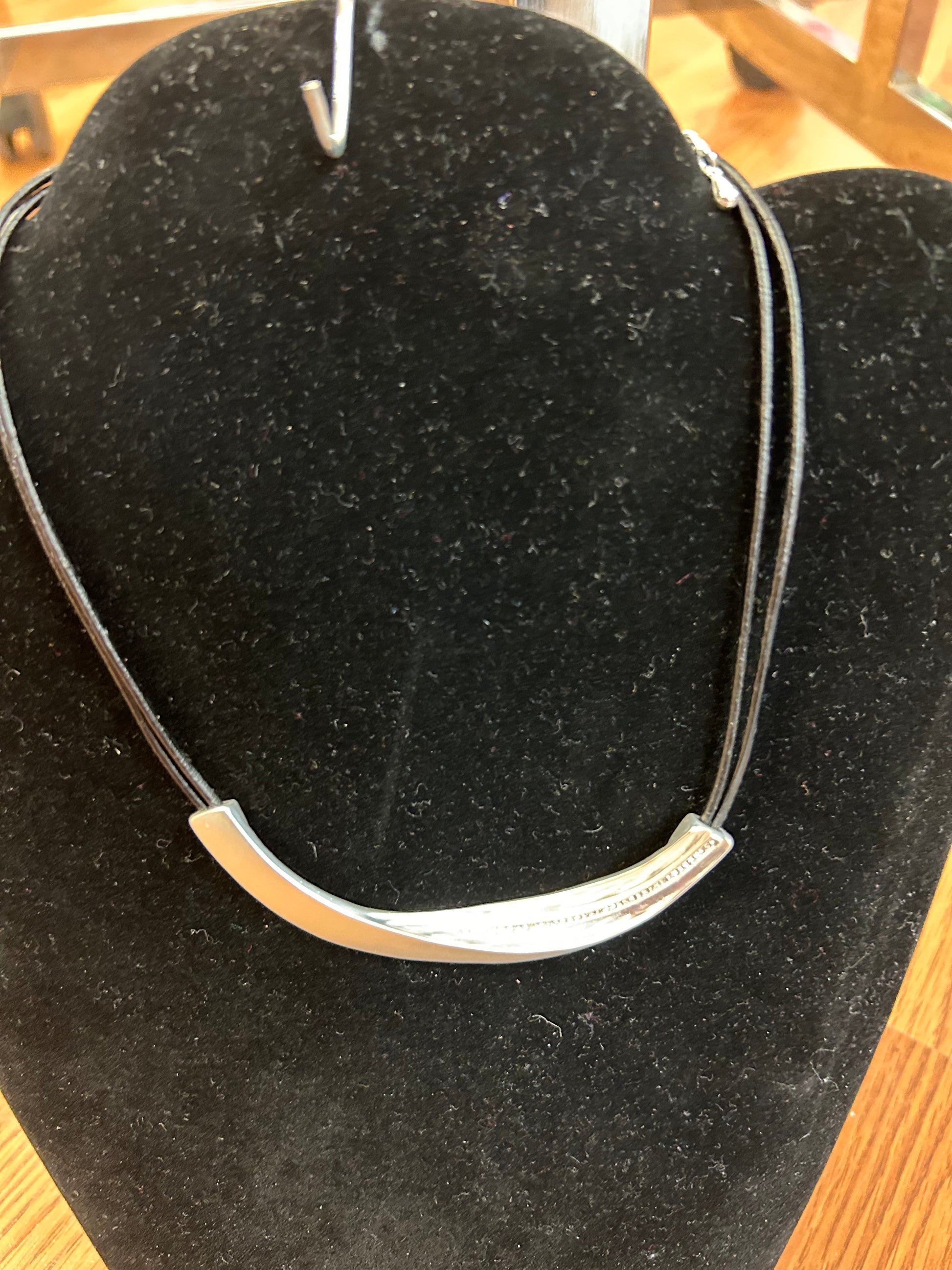 Curved silver bar with stones on a short black cord. adjustable from 16 to 18 inches